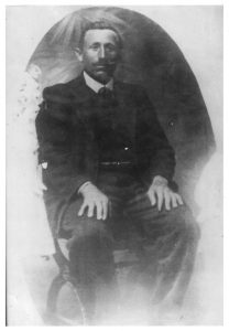 Fotografia d'epoca di Aristide Incerti Rinaldi. Rappresenta un uomo con baffi e capelli scuri, in abiti eleganti, seduto con le mani posate sulle ginocchia.